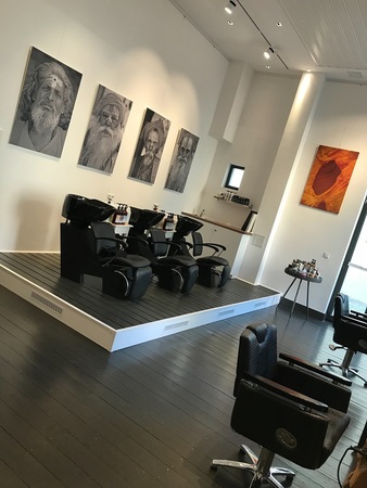 Moderner Friseursalon mit Waschplätzen, Friseurstühlen und Wandbildern im Innenraum.