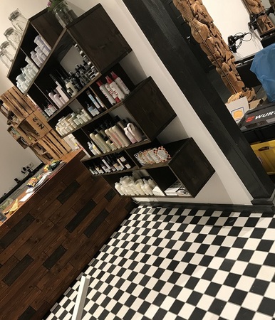 Regal mit Haarpflegeprodukten und Kosmetik in einem modernen Friseursalon mit Retro-Fliesen.