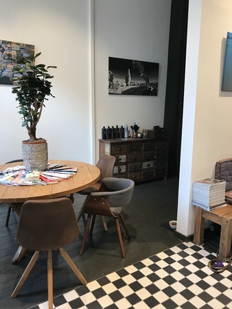 Moderner Wartebereich mit Holztisch, Stühlen, grüner Pflanze und Zeitschriften.