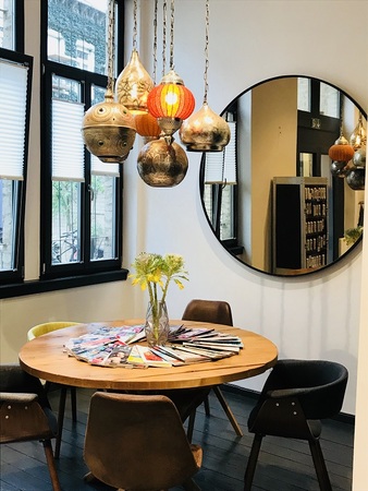 Moderner Essbereich mit Holztisch, bunten Stühlen, Blumen, Zeitschriften und Pendelleuchten.